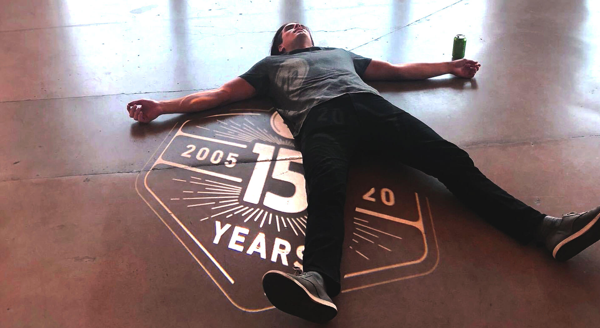 A man laying on the floor with the TJA 15th Anniversary logo projected on his body
